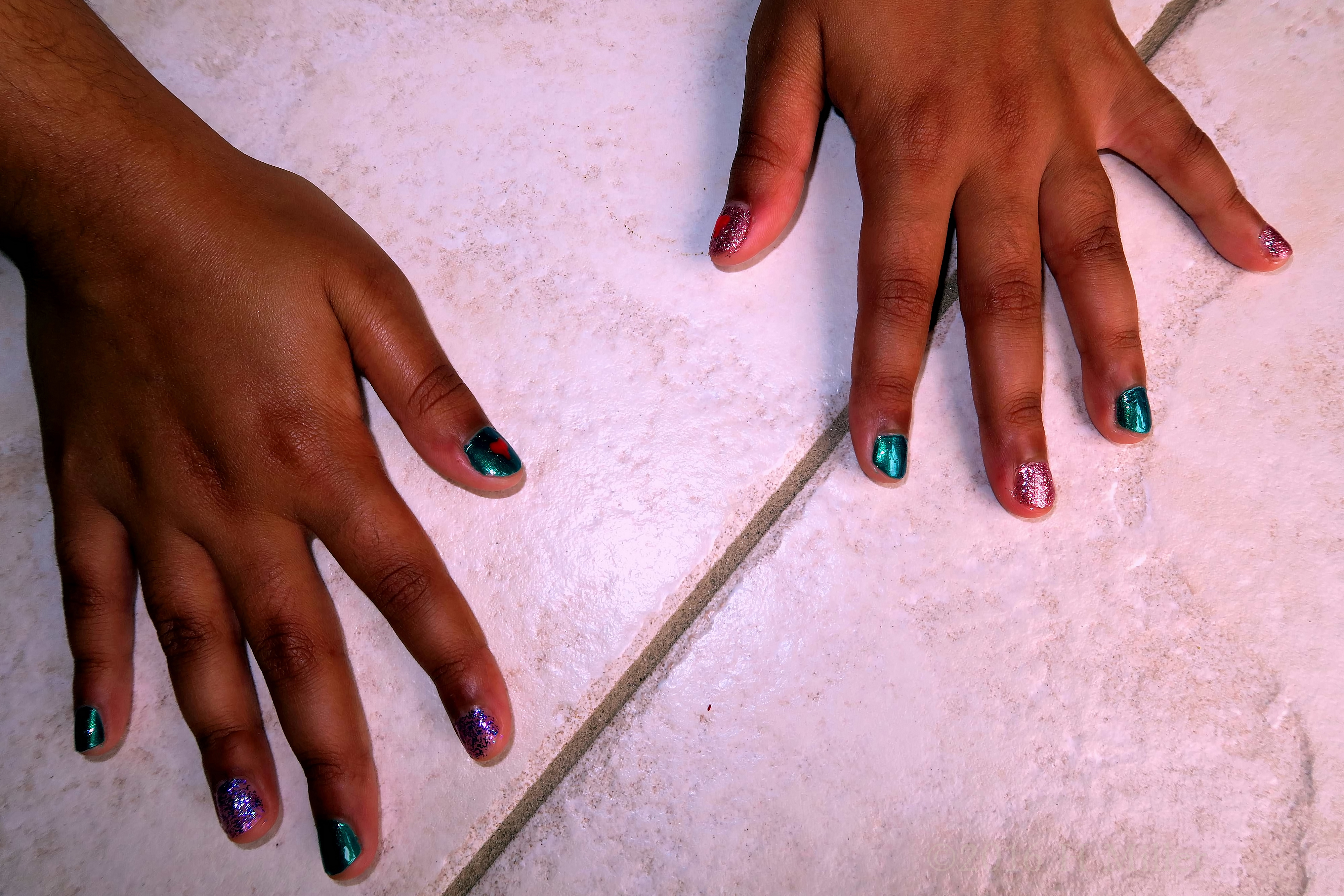 Kids Mini Mani With Hearts And Metallic Green Polish, Alternating With Clear Purple Glitter. Kids Mini Mani With Hearts And Metallic Green Polish, Alternating With Clear Purple Glitter.