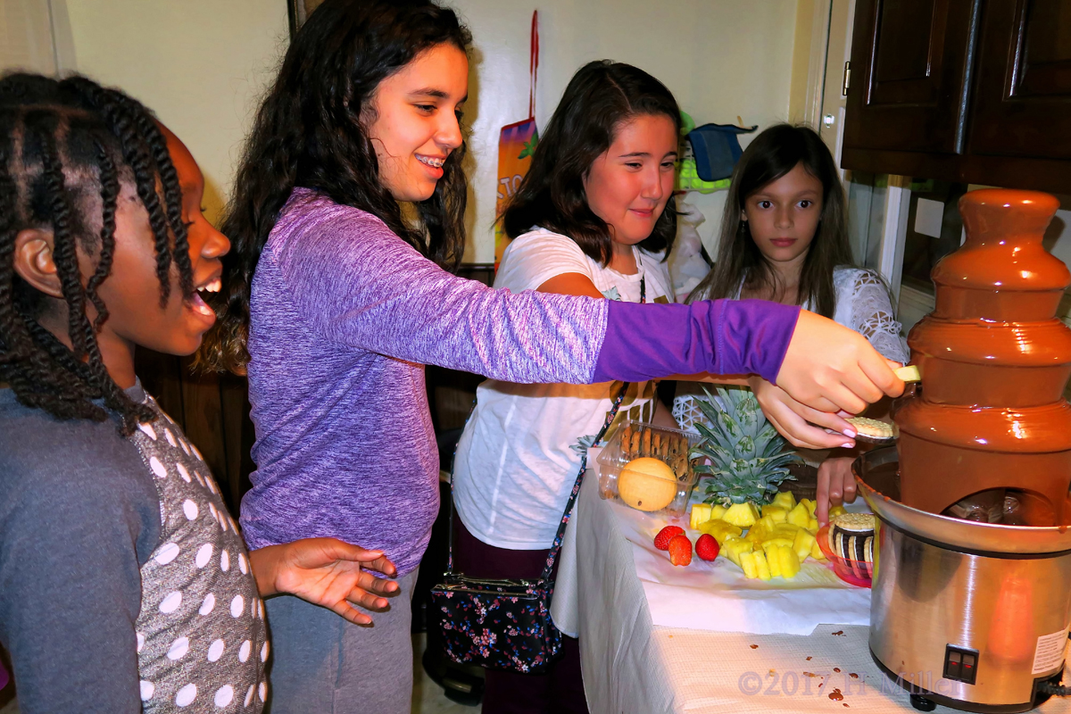 Chatting While Dipping Fruit In The Chocolate Fountain.