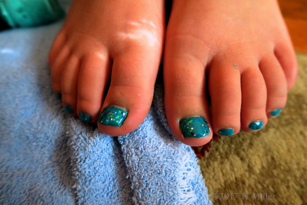 Close Up Of Glossy Blue Girls Pedicure With A Glitter Top Coat.