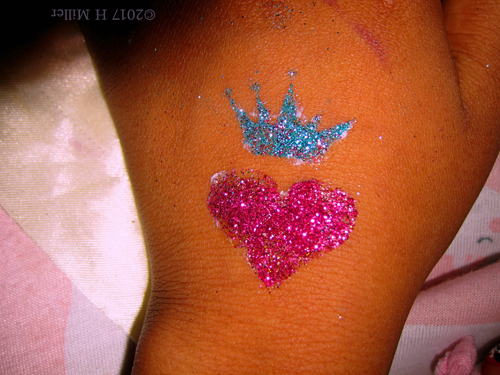 Glittery Heart And Crown Temporary Tattoo On Her Hand.