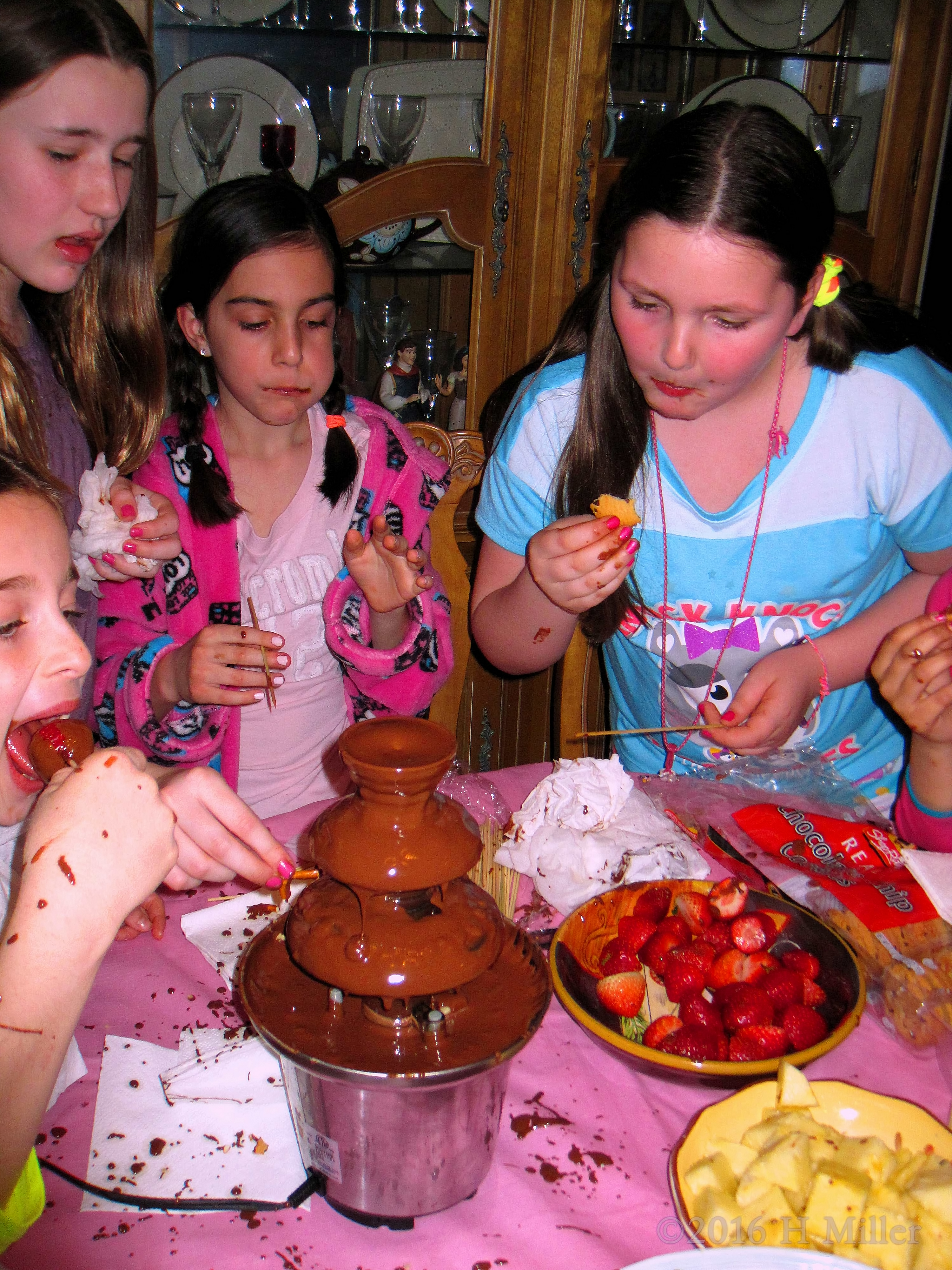 A Picture Capturing The Party Guests Enjoying The Chocolate Fondue Fountain And Snacks A Picture Capturing The Party Guests Enjoying The Chocolate Fondue Fountain And Snacks