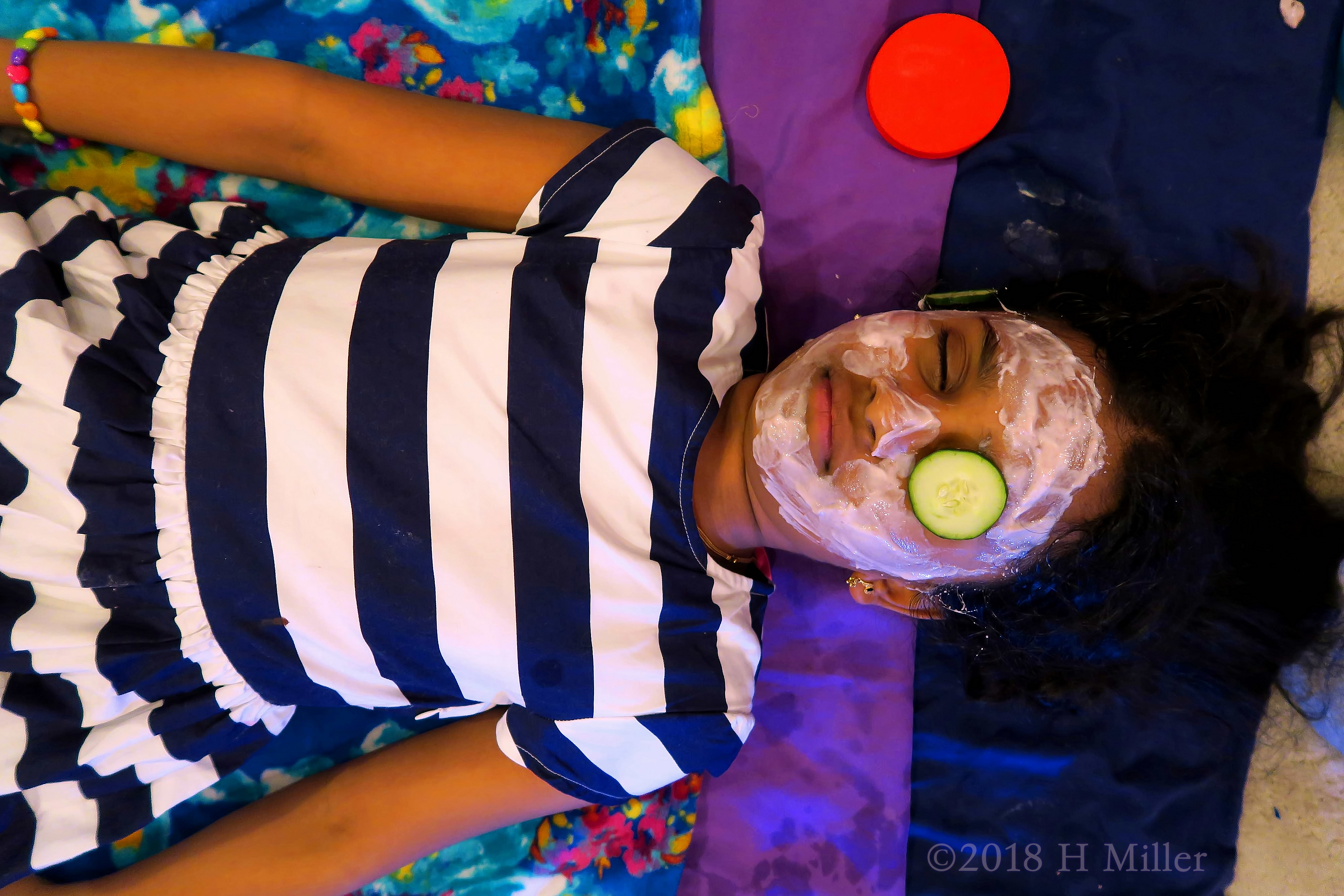 Lying On The Kids Facial Mat With The Facial Masque On And A Cuke Over Her Eye. Lying On The Kids Facial Mat With The Facial Masque On And A Cuke Over Her Eye.