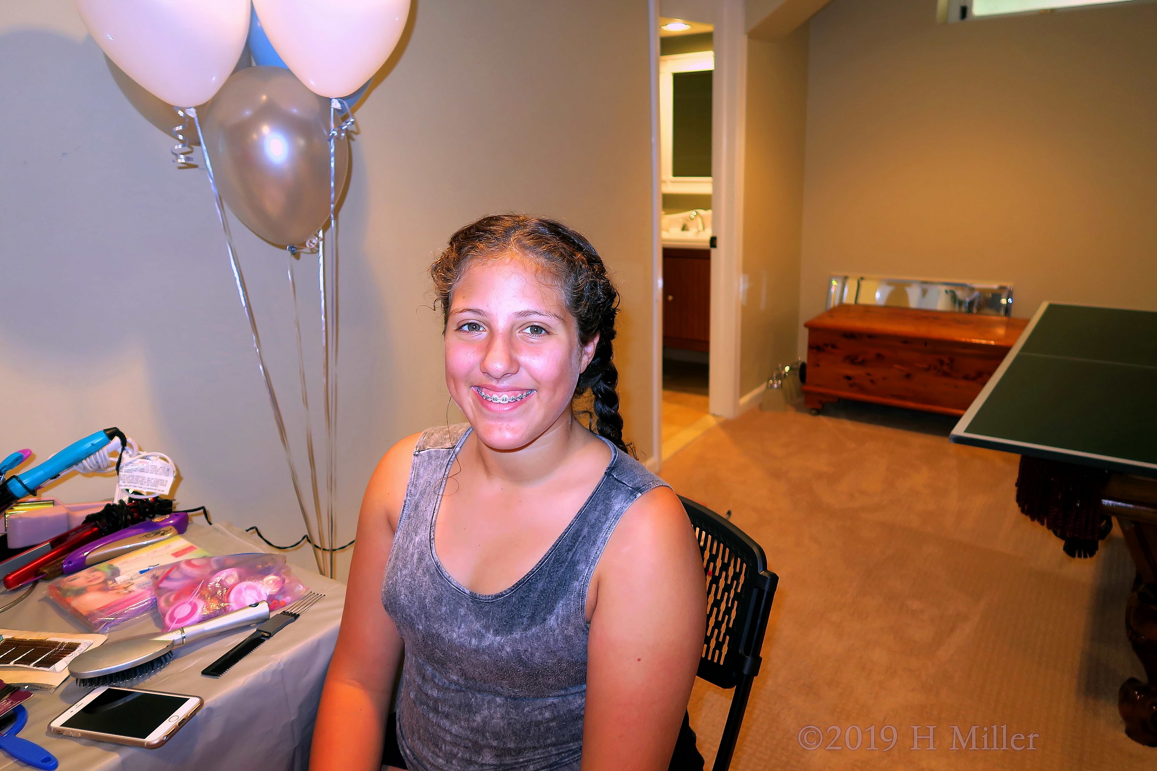 Girl Smiling At The Kids Hair Salon With White Blue Silver Colored Balloons In The Background 