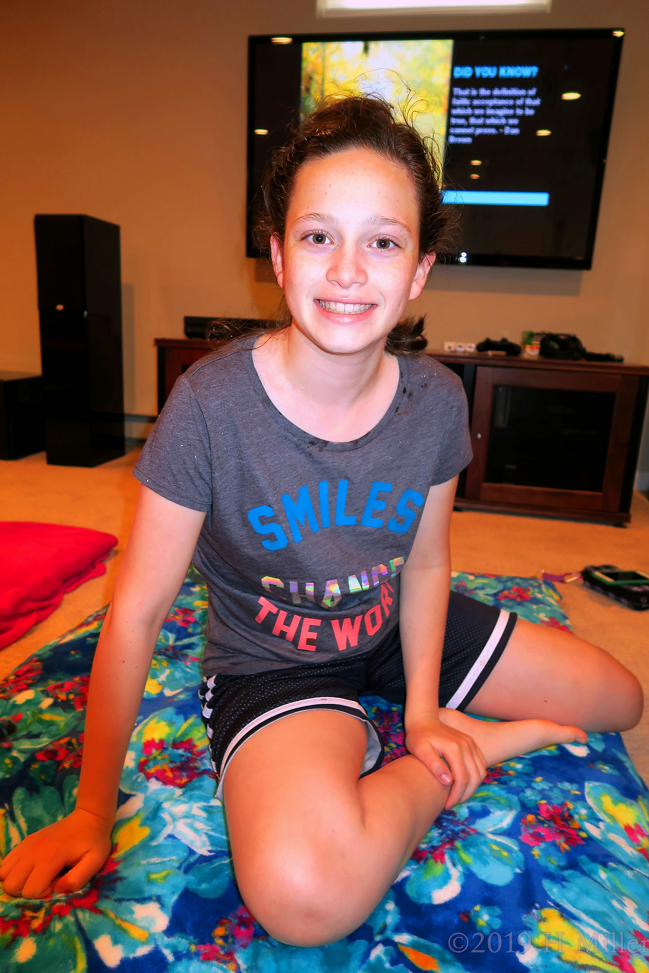Girl Smiling And Sitting On Multicolor Blue Red And Yellow Spa Mat After Facials For Kids. 