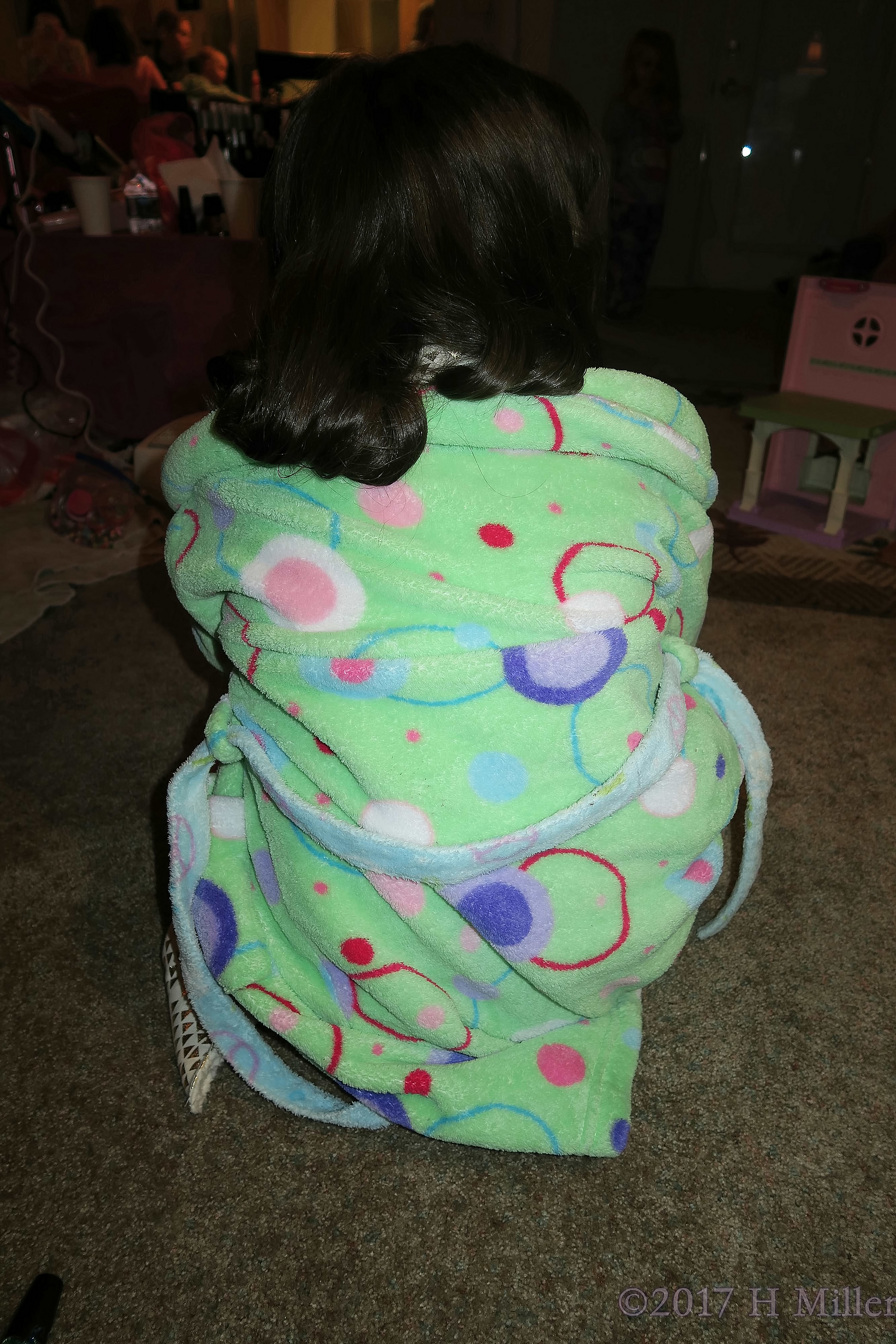 Fluffy Green Spa Robe With Orange And Blue Designs, Showing Off Her Curled Kids Hairstyle. 