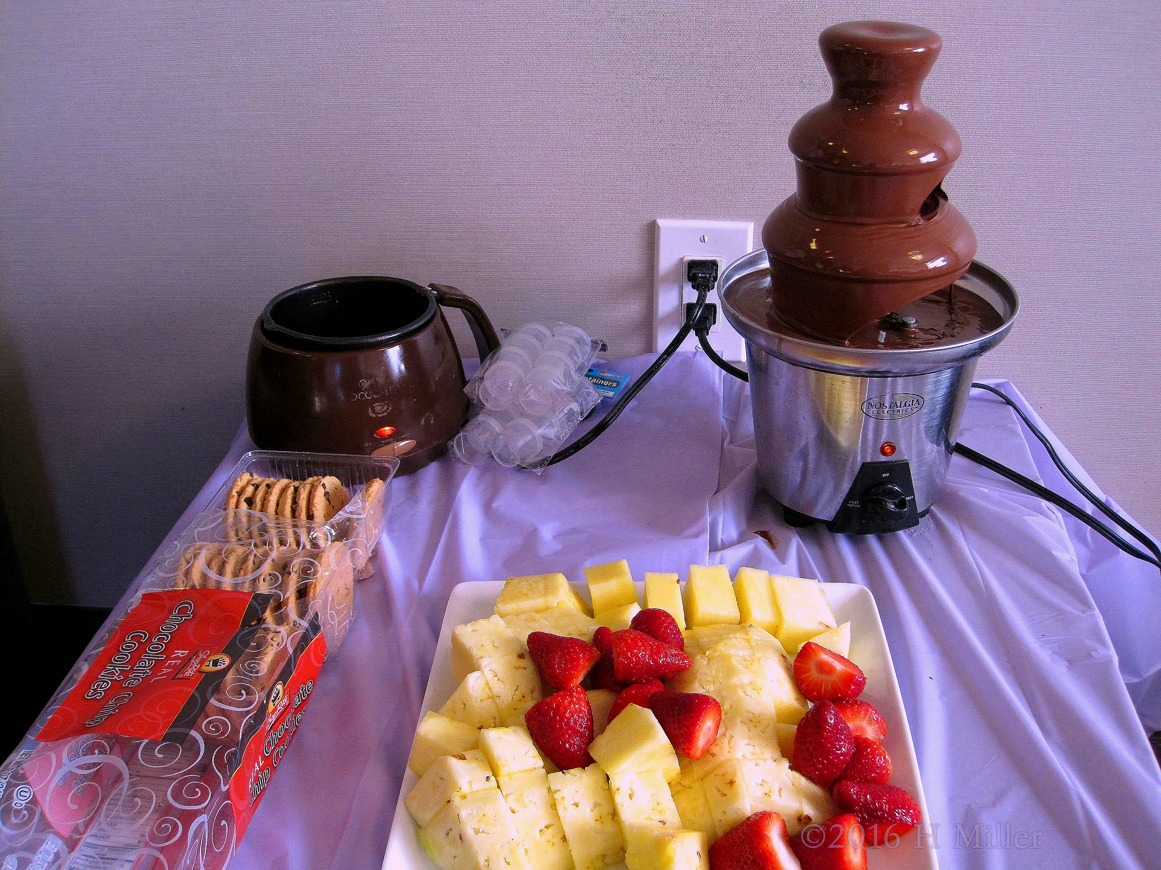 Chocolate Fondue Fountain With Pineapples, Strawberries, And Cookies For The Spa Party For Kids. Chocolate Fondue Fountain With Pineapples, Strawberries, And Cookies For The Spa Party For Kids.