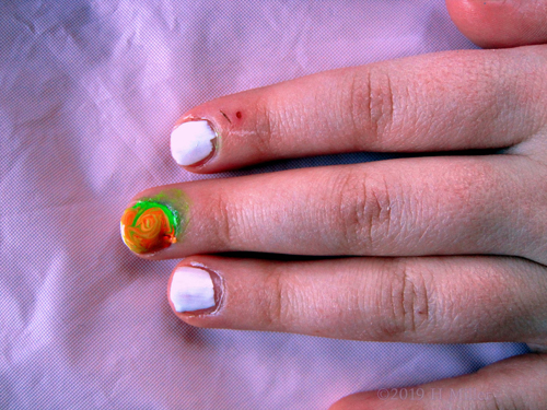 Kids Manicure With White, Plus A Multicolor Marbled Nail Design With Green And Orange Swirls