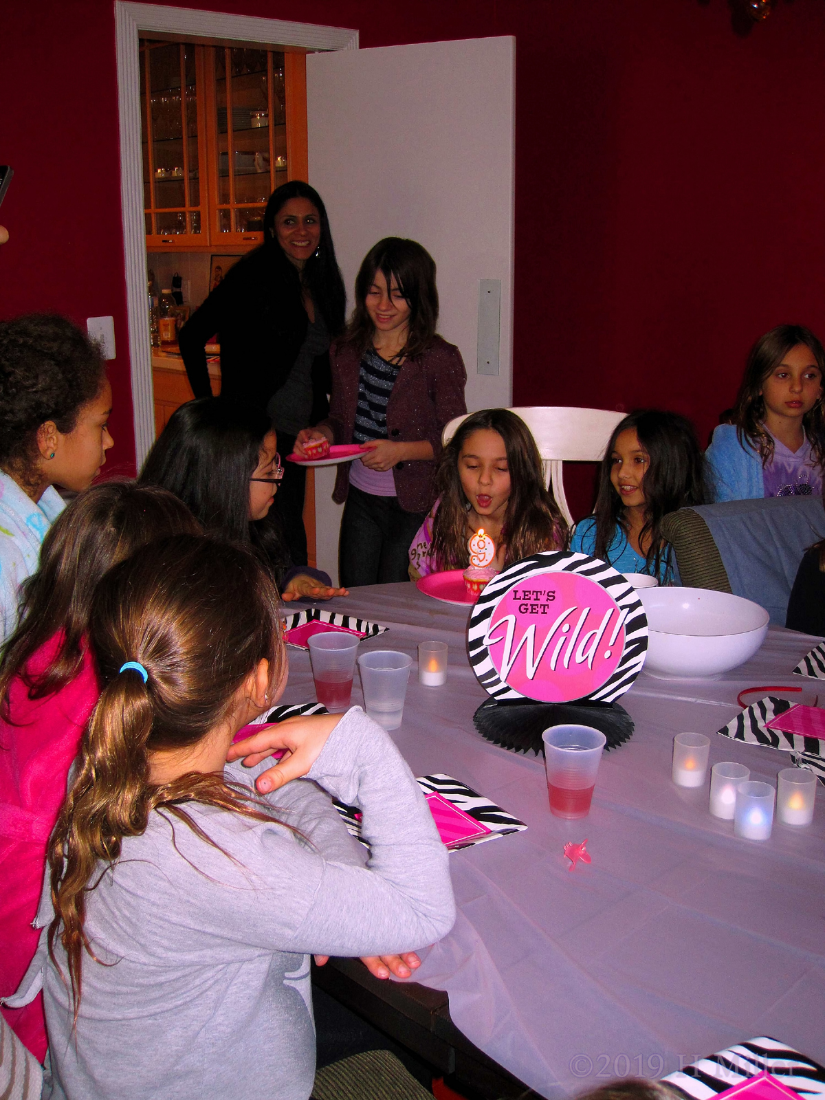 Birthday Girl Blows Out Her Candles While Her Happy Friends Watch 