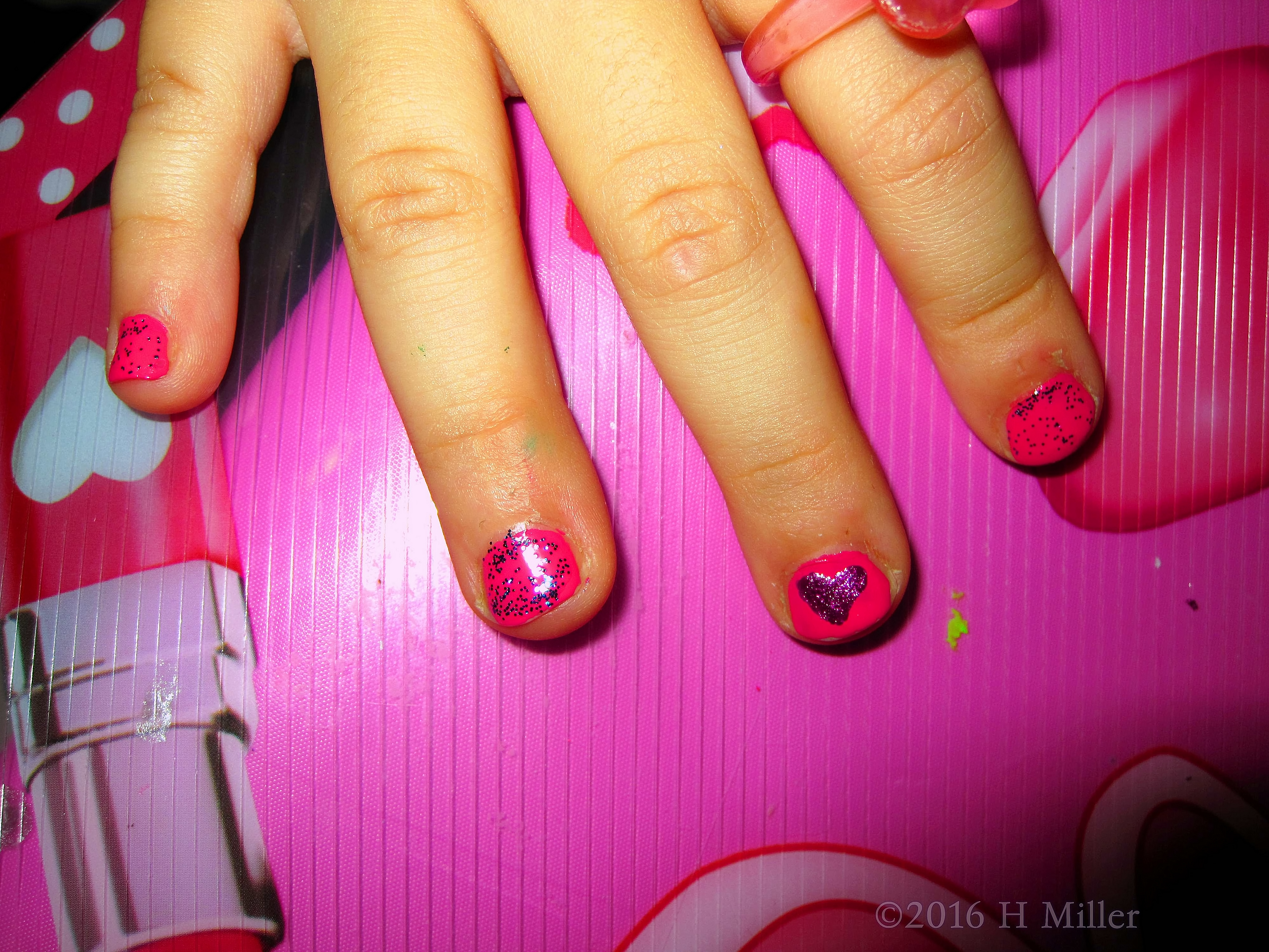 Kids Manicure Featuring Glitter On A Pink Background With Beautiful Heart Nail Art
