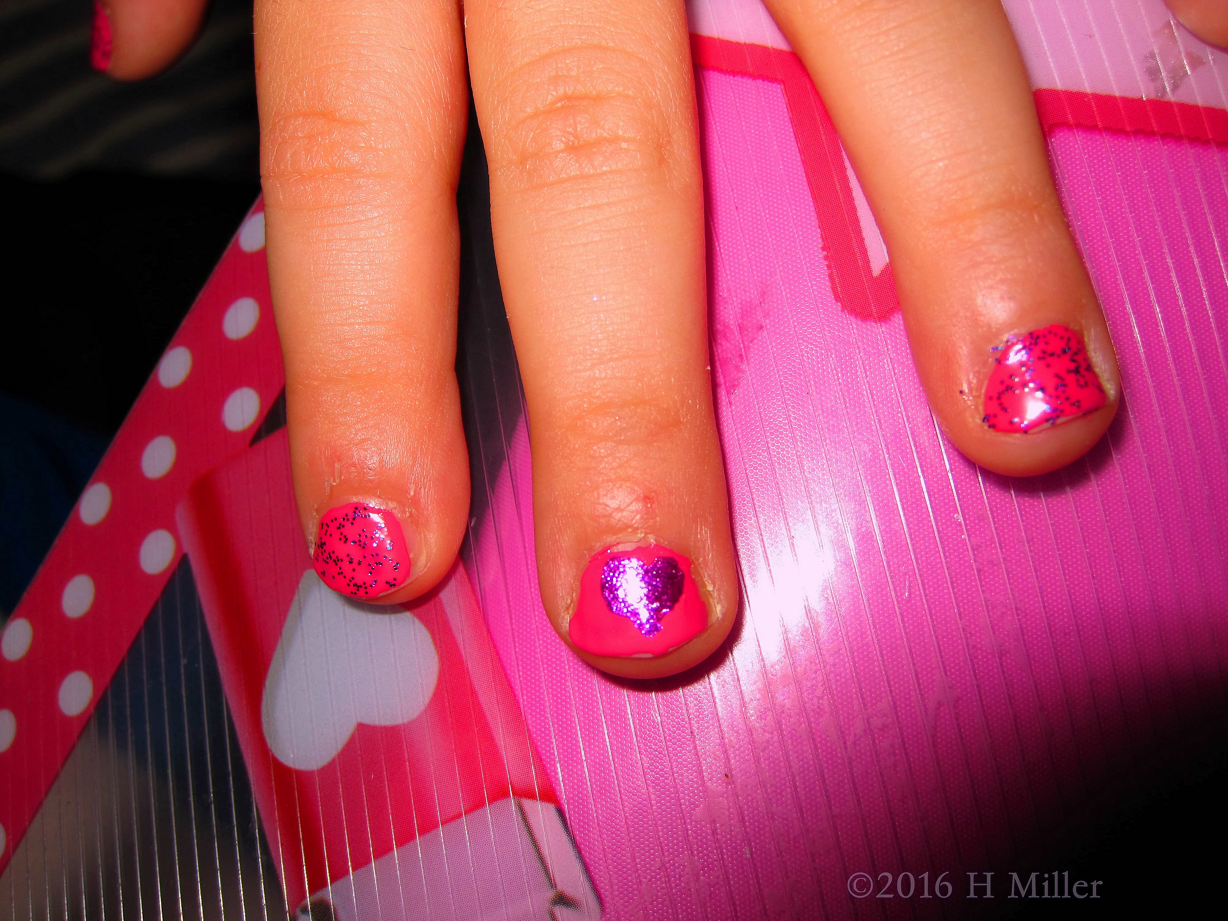 Kids Manicure With Nail Design Of A Purple Heart On A Pink Background