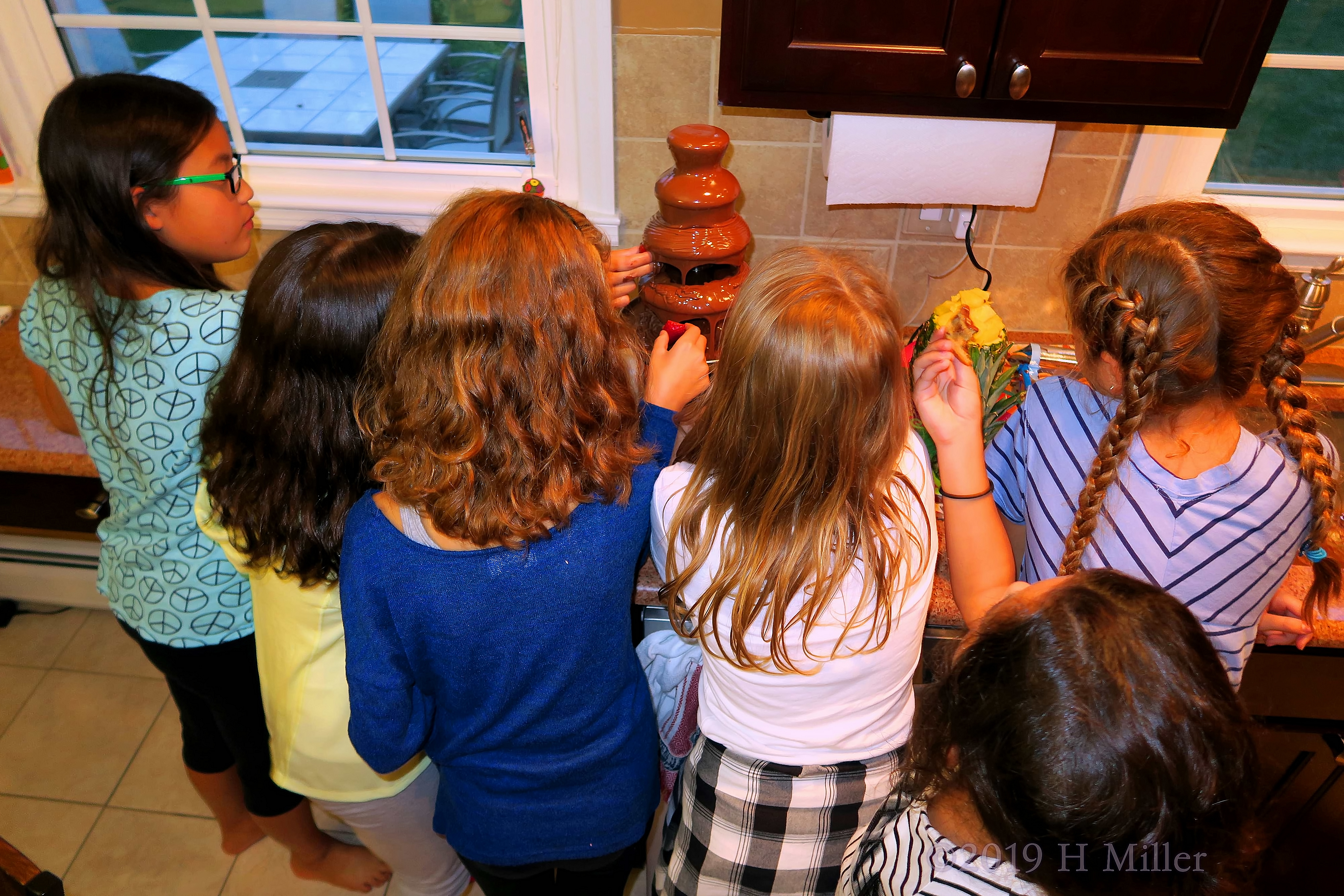 The Girls Dipping Their Fruit And Cookies Into The Chocolate Fountain 