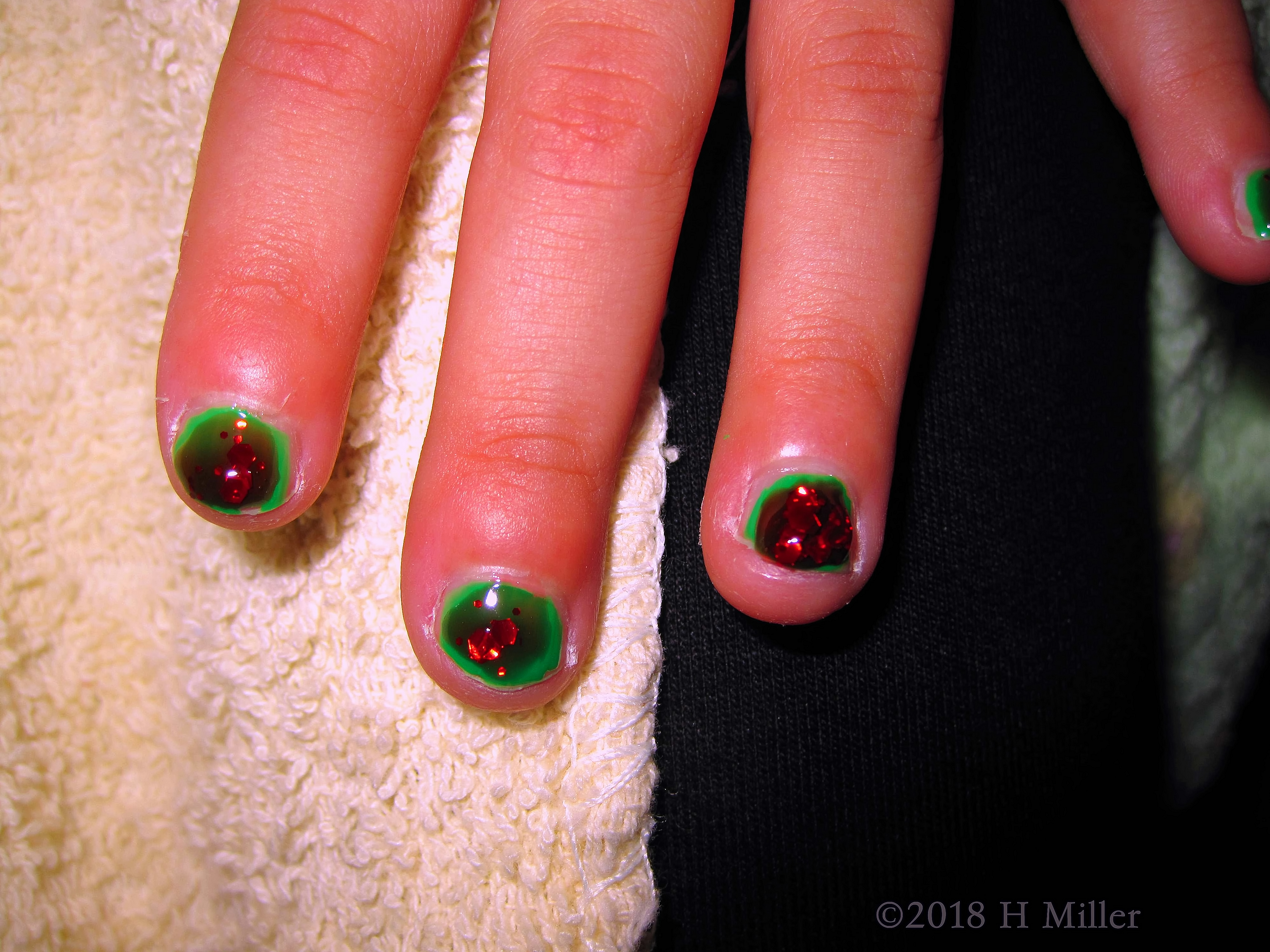 Cute Kids Manicure With Red Glitter Over Green. Cute Kids Manicure With Red Glitter Over Green.