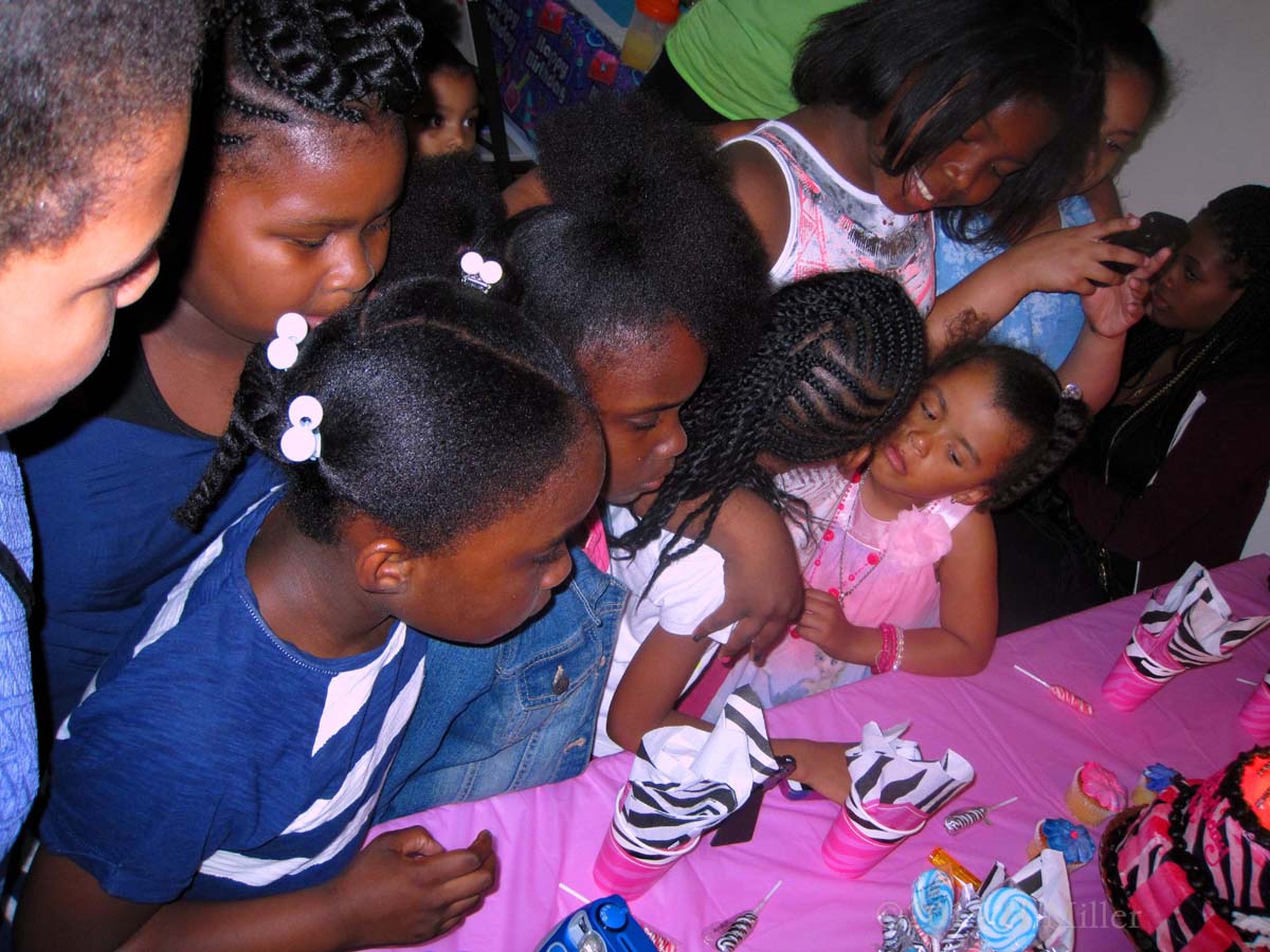 Crowding Together At The Birthday Cake Table Ready To Sing 