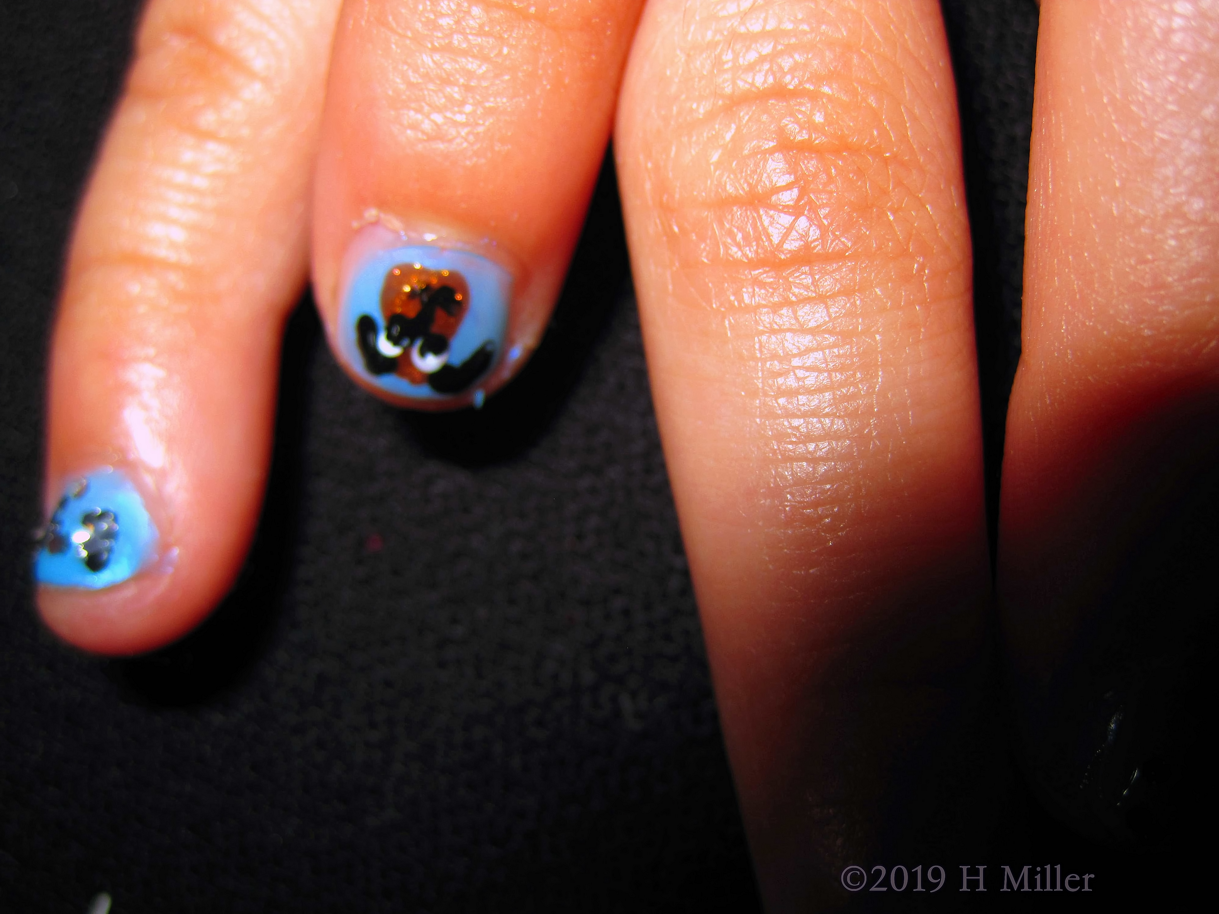 A Little Bunny Face Nail Art On Blue Girls Manicure. 