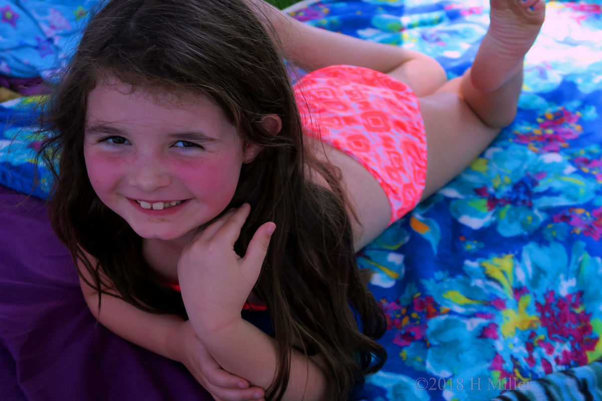 The Birthday Girl Is Smiling While Lying Down On The Facial Mat 