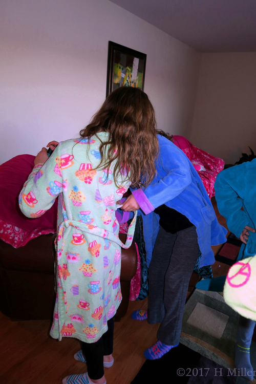 Party Guests Helping Each Other Out With Their Spa Robes