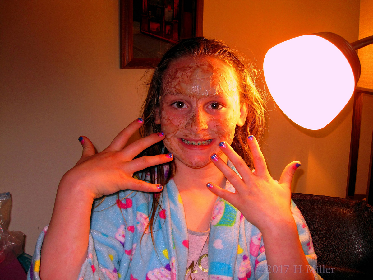 Party Guest Showing Off Her Ombre Kids Nail Design While Comfy In Her Spa Robe And Face Mask 1