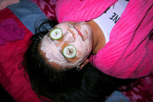 Party Guest Having Fun With Kids Facial And Soothing Cucumber Slices On The Eyes